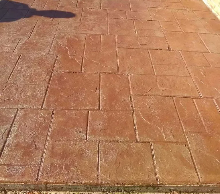Red stamped concrete walkway with ashlar pattern